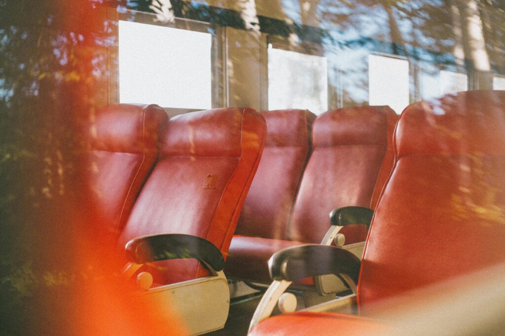 Interior view of empty red leather seats on a public transport vehicle.